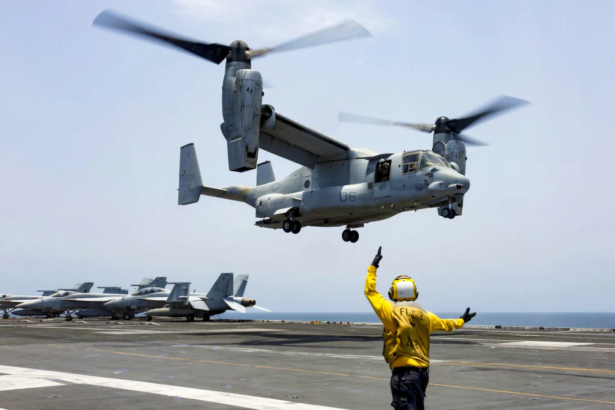 Aviation Boatswain's Mate 2nd Class Nicholas Hawkins signals an MV-22 Osprey to land on the flight deck of the USS Abraham Lincoln in the Arabian Sea on May 17, 2019.  (Mass Communication Specialist 3rd Class Amber Smalley/U.S. Navy via AP)