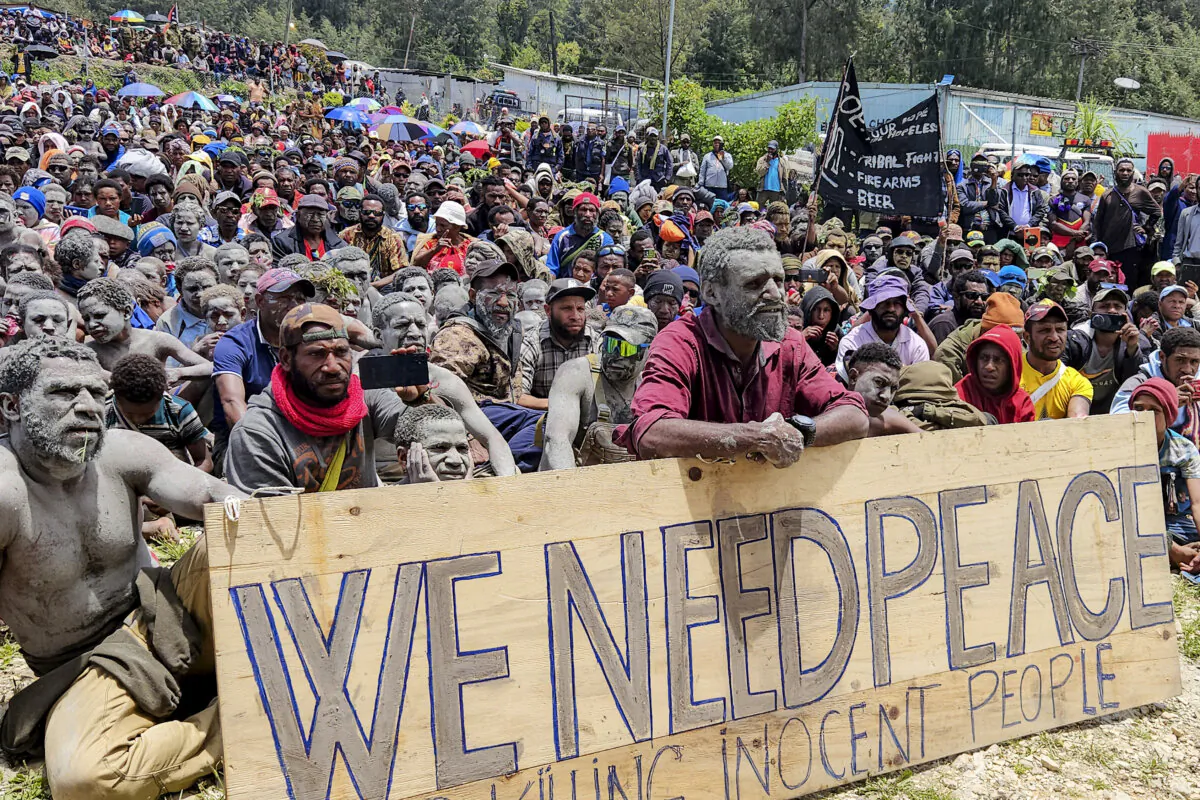 Local villagers hold a placard as they participate in a gathering near the Porgera Gold Mine in Porgera in the central highlands of Papua New Guinea on September 23, 2024, almost one week after police reinforcements were rushed to the area in a bid to quell tribal violence that shuttered the key gold mine. Days of tit-for-tat shootouts between hundreds of tribal warriors have left at least 32 people dead in the mine's vicinity. Hundreds more have been displaced by the violence. (Photo by AFP) (Photo by STR/AFP via Getty Images)