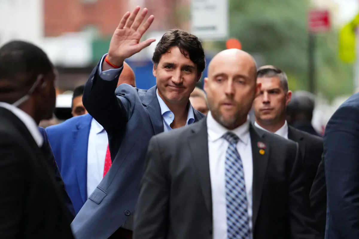Prime Minister Justin Trudeau, flanked by entourage and security, waves as he arrives at the CBS studios for the filming of "The Late Show with Stephen Colbert," in New York, Monday, Sept. 23, 2024. Trudeau was interviewed by Colbert, and the episode aired later that night. (THE CANADIAN PRESS/Sean Kilpatrick)