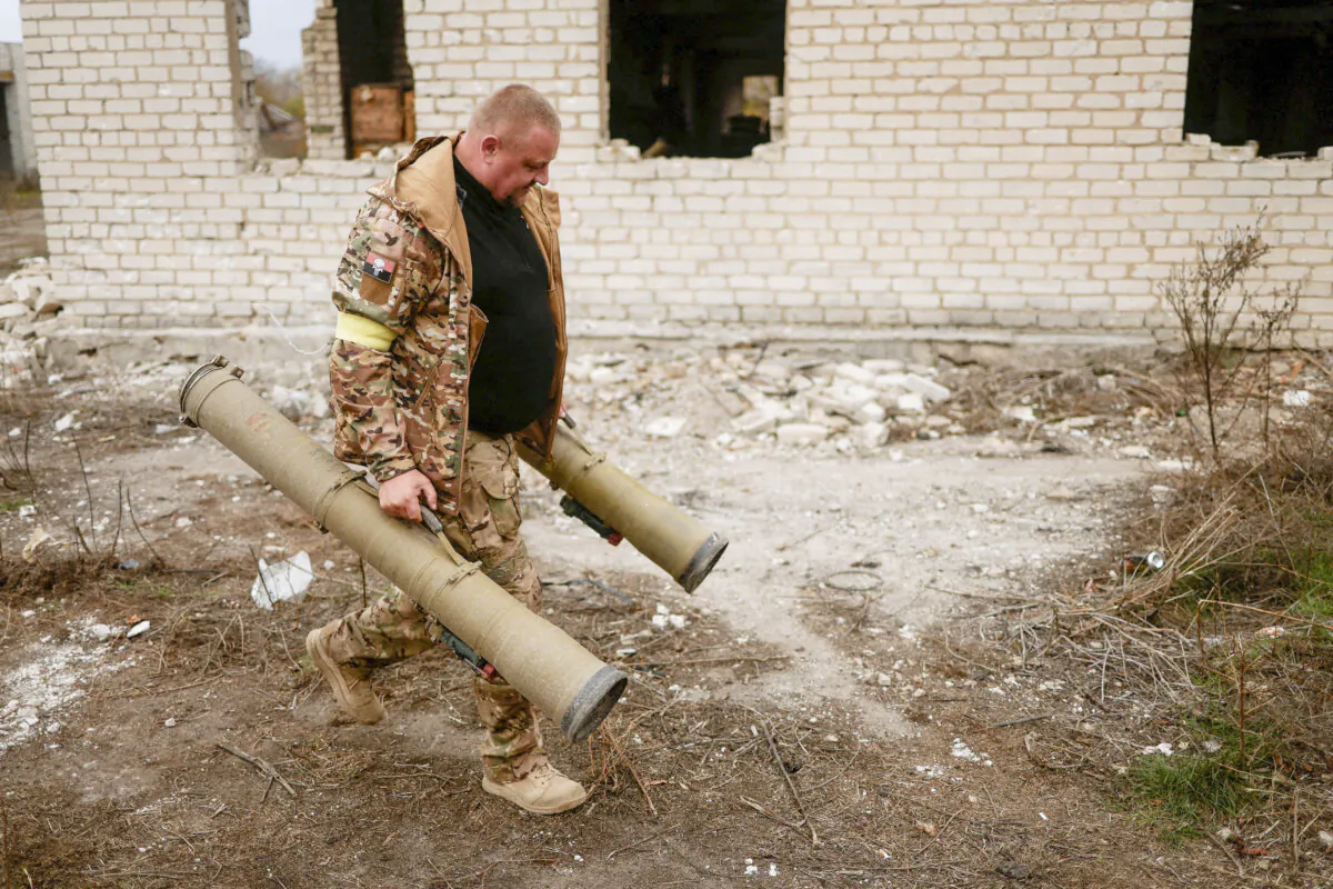 A Ukrainian serviceman carries captured anti-tank grenade launchers at a former position of Russian soldiers in the village of Blahodatne in Kherson region, Ukraine, Nov. 11, 2022. (Valentyn Ogirenko/Reuters)