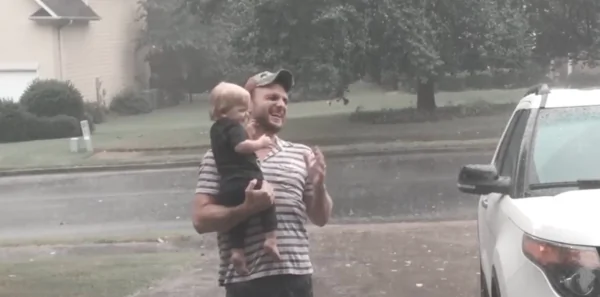 Baby Plays in Summer Rain With Father