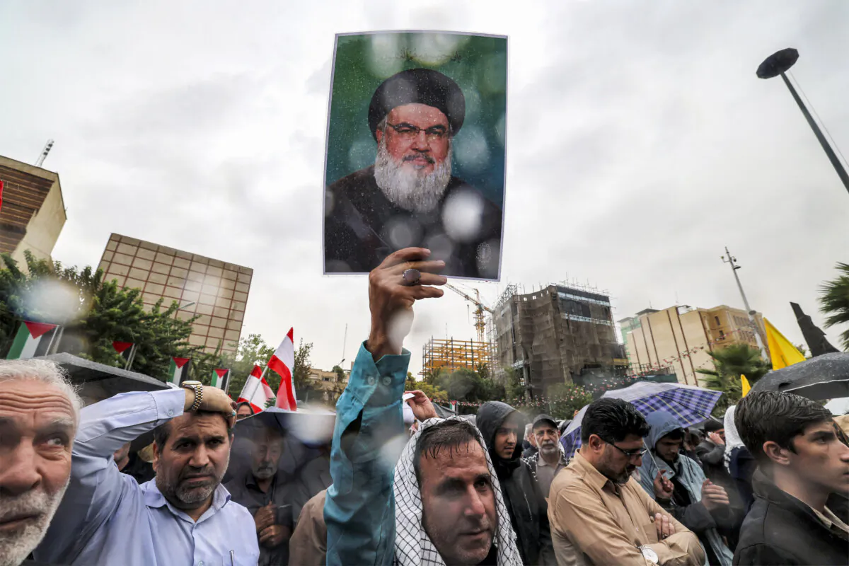 A demonstrator stands in the rain holding up a a picture of late Lebanese Hezbollah leader Hassan Nasrallah during an anti-Israel protest in Tehran's Palestine Square, Iran, on Sept. 28, 2024. (Atta Kenare/AFP via Getty Images)
