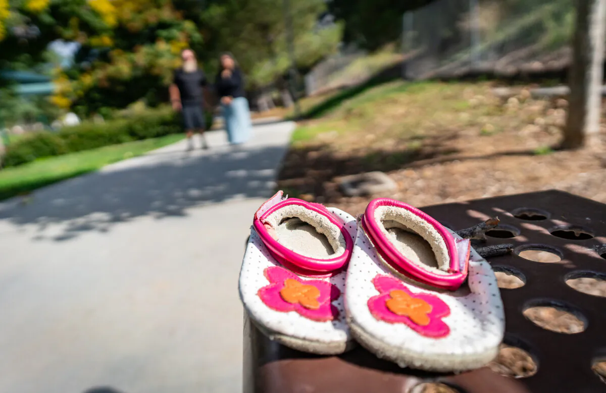 Parents stand behind the baby shoes of their daughter near their home in Santa Clarita, Calif., on Oct. 9, 2023. (John Fredricks/The Epoch Times)