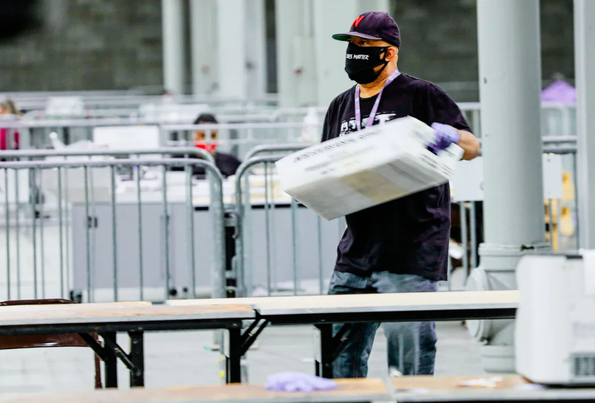 A worker carries a bin of ballots to be scanned at the Georgia World Congress Center in Atlanta on Jan. 5, 2021. (Sandy Huffaker/AFP via Getty Images)