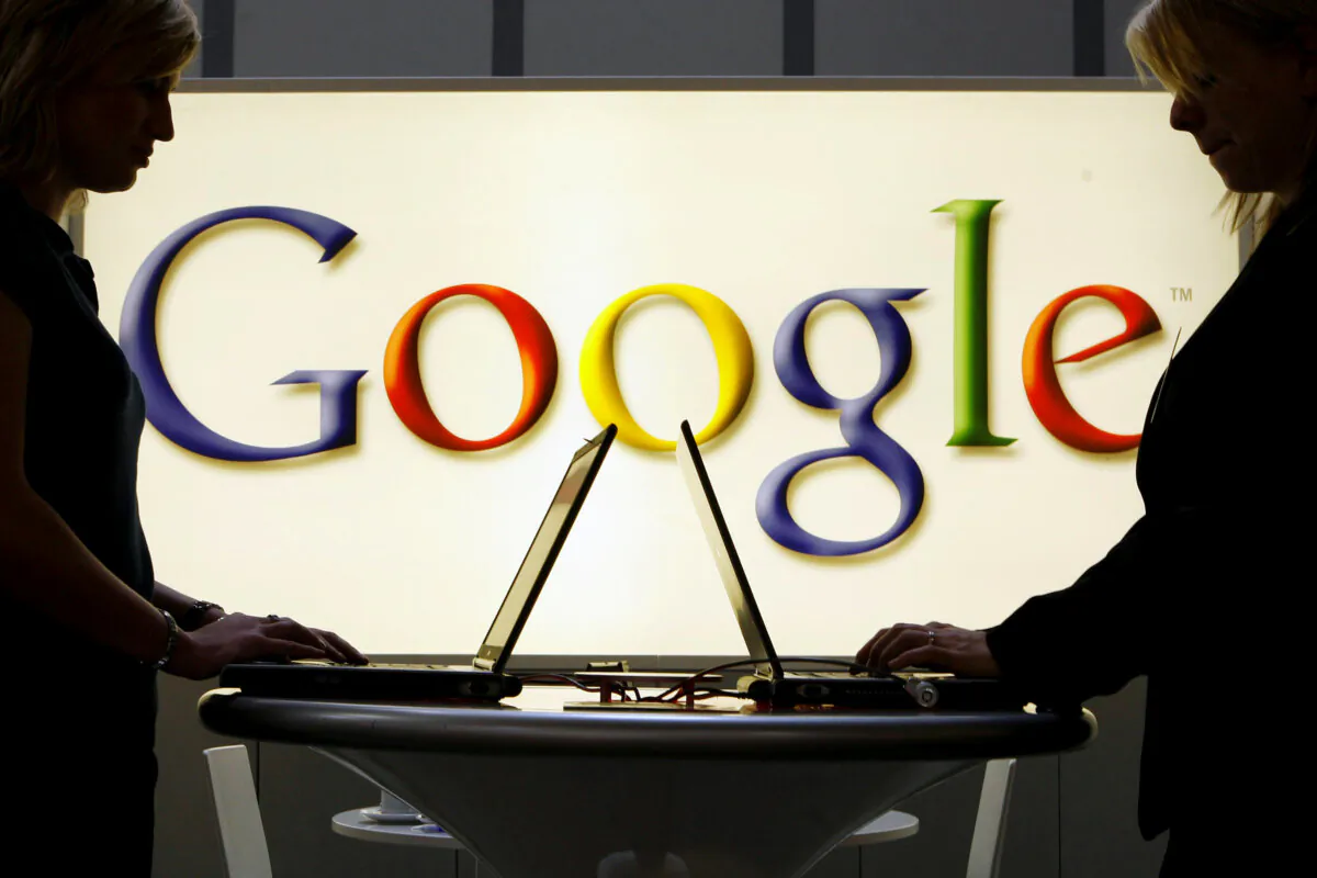 The exhibitors work on laptop computers in front of an illuminated sign of the Google logo at the industrial fair Hannover Messe in Hanover, Germany, on April 17, 2007. (Jens Meyer/AP Photo)