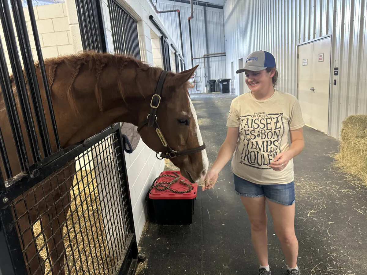 Maggie Nelson feeds a snack to her horse, Edna, where she sought shelter from Hurricane Helene, at the World Equestrian Center in Ocala, Fla., on Sept. 27, 2024. (Nanette Holt/The Epoch Times)