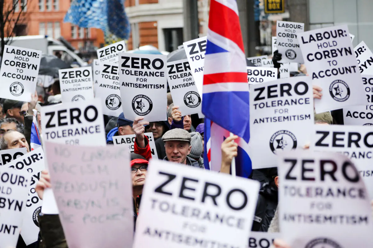 People hold up placards and Union flags as they gather for a demonstration organised by the Campaign Against Antisemitism outside the head office of the Labour Party in London, on April 8, 2018. (Tolga Akmen/AFP/Getty Images)