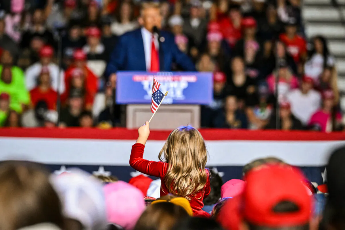 A child holds up an American flag as Republican presidential candidate and former President Donald Trump speaks during a campaign rally at Saginaw Valley State University in Saginaw, Mich., on Oct. 3, 2024. (Jim Watson/AFP via Getty Images)