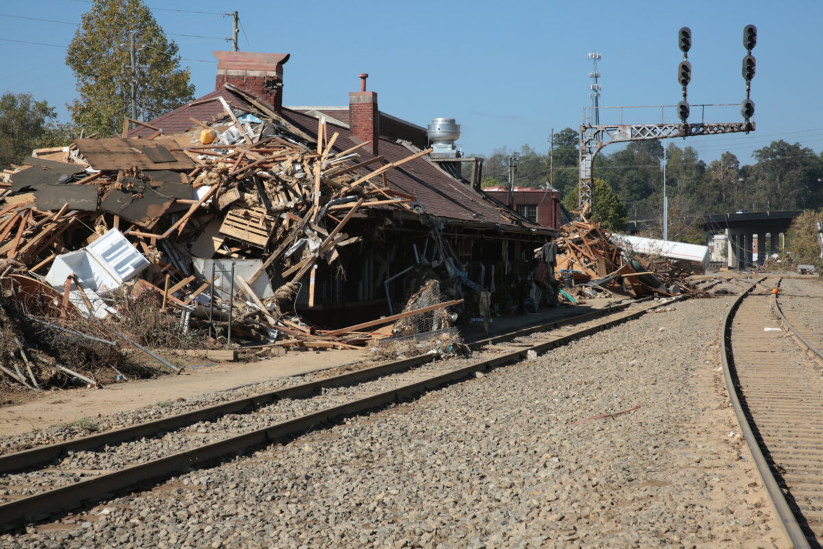 Debris piled high by floodwaters against a railway building in Biltmore Village, Asheville, N.C, on Oct. 5, 2024. (Richard Moore/The Epoch Times)