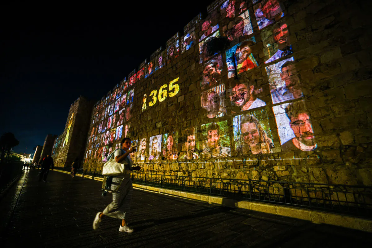 People walk past a projection of photos of victims from Hamas's attack on Israel on Oct. 7, 2023, on a wall in Jerusalem on Oct. 6, 2024. (Ahmad Gharabli/AFP via Getty Images)