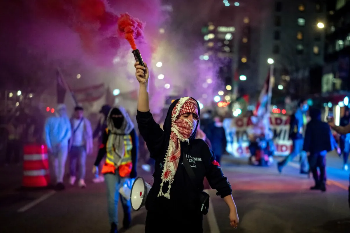 A demonstrator holds a smoke bomb while marching during a pro-Palestine rally marking the anniversary of the Hamas attack on Israel last October, in Vancouver on Oct. 7, 2024. (The Canadian Press/Ethan Cairns)