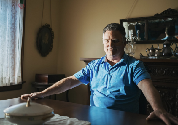 Man in blue shirt at a table in "Heart of a Servant - The Father Flanagan Story."