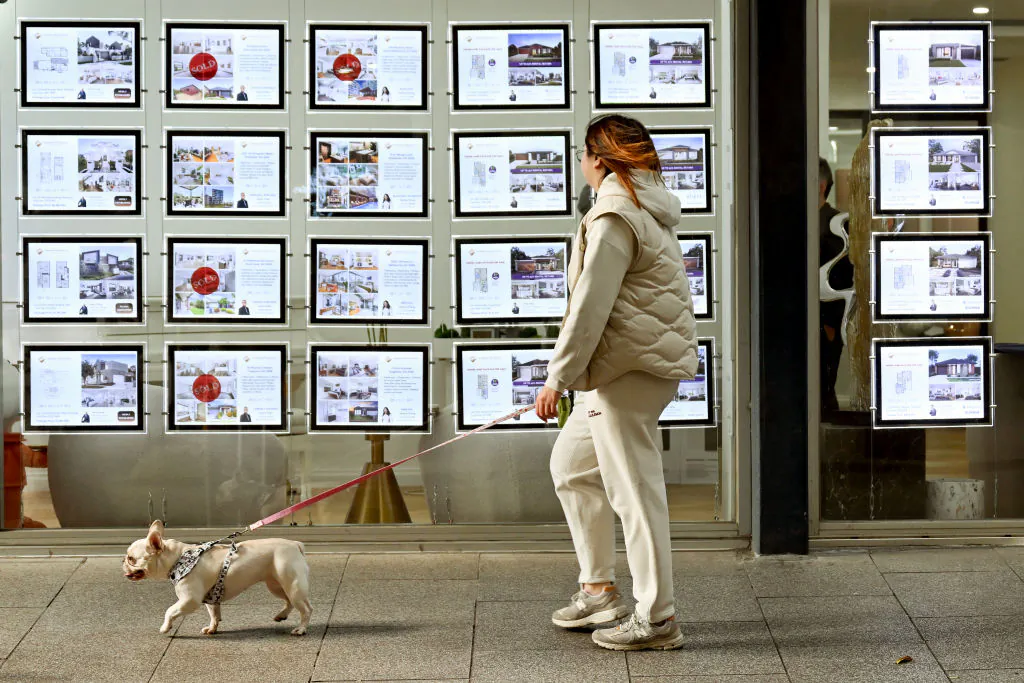 A woman and her dog walk past a real estate agents display in Melbourne, Australia on Aug. 6, 2024. (William West/AFP via Getty Images)