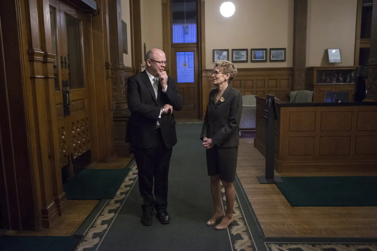Then-Ontario Premier Kathleen Wynne talks to then-Principal Secretary Andrew Bevan as they wait for the arrival of then-Quebec Premier Philippe Couillard at the Queen's Park Ontario Legislature in Toronto on Nov. 21, 2014. (Chris Young/The Canadian Press)