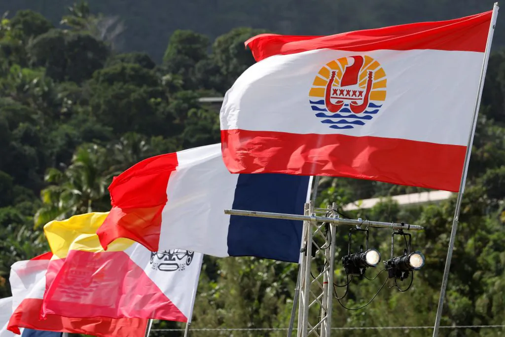 From front to back: the flags of French Polynesia, France, and the Marquesas Islands are seen from the bleachers ahead of the arrival of France's President Emmanuel Macron at the Hiva Oa stadium in the Marquesas Islands, French Polynesia on July 25, 2021. (Ludovic Marin/AFP via Getty Images)
