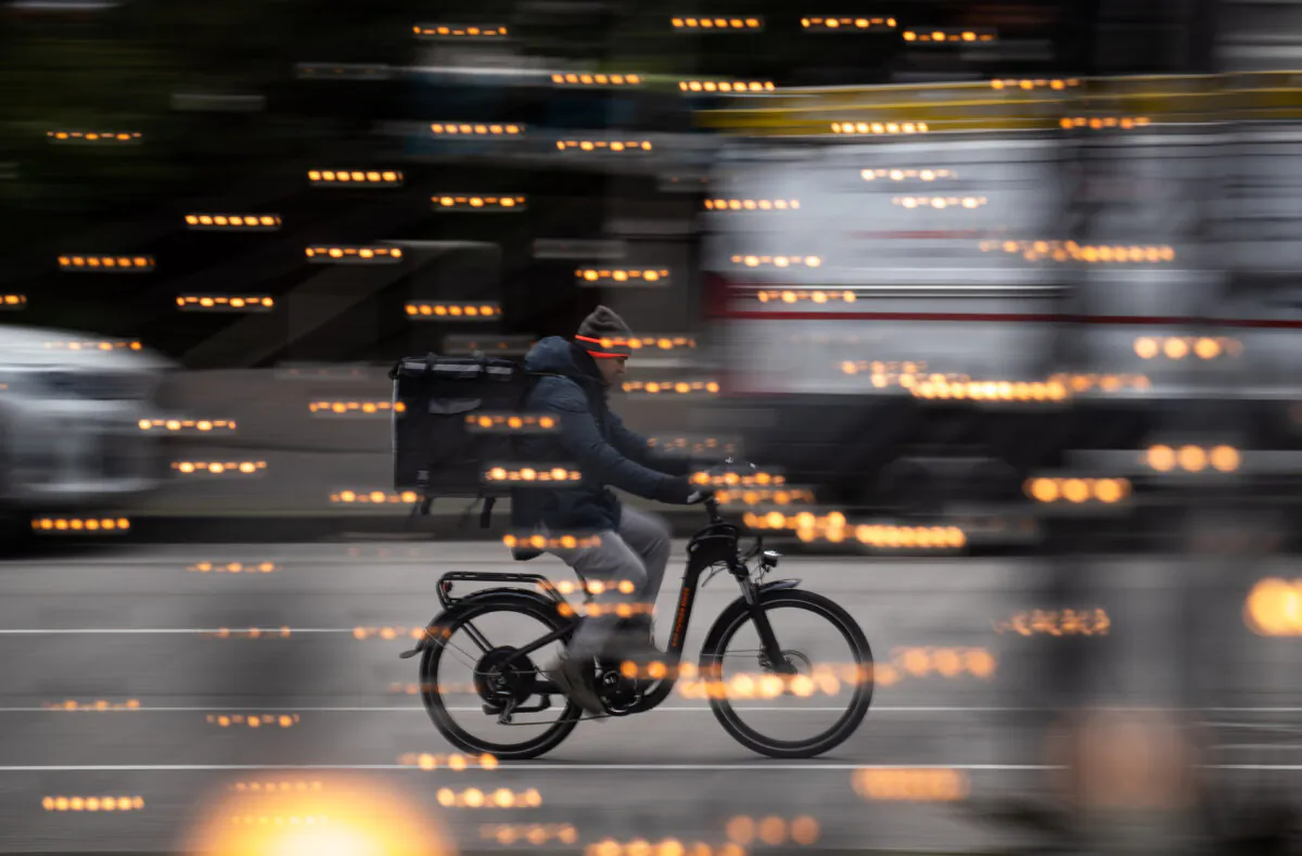A food delivery worker rides a bike in downtown Vancouver, on Dec. 23, 2021. (The Canadian Press/Darryl Dyck)