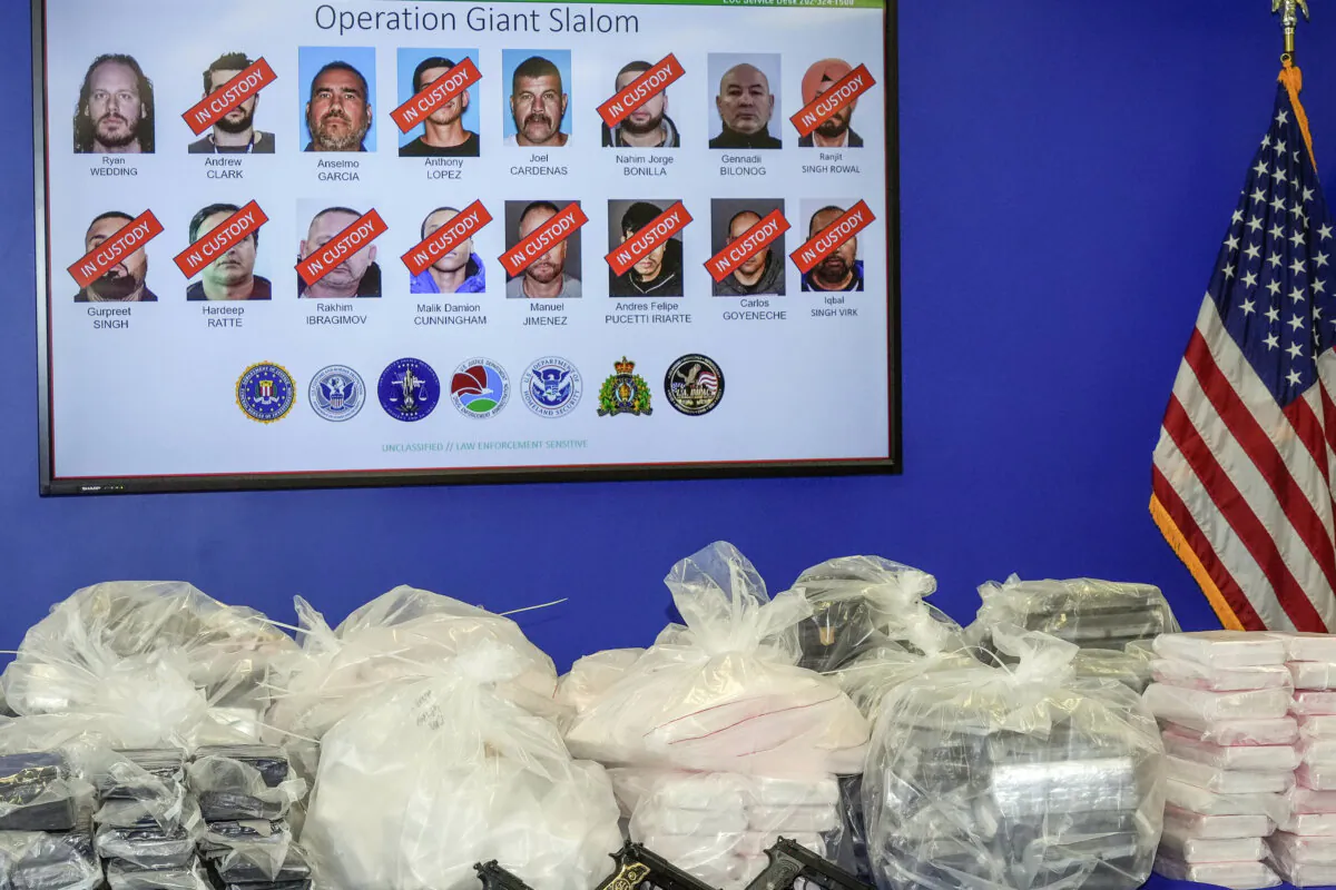 A photo of former Canadian Olympic snowboarder Ryan Wedding, 43, who is a fugitive, is seen top left, with 15 other defendants who have been charged with allegedly running and participating in a transnational drug trafficking operation, is displayed on a video monitor at a news conference at the FBI offices in Los Angeles, Oct. 17, 2024. (AP Photo/Damian Dovarganes, File)