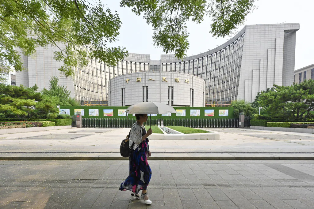 A woman walks past the central bank in Beijing on July 9, 2024. (Adek Berry/AFP via Getty Images)