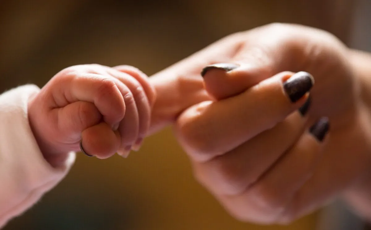 An undated file photo of a baby grabbing its mother's fingers. (PA)