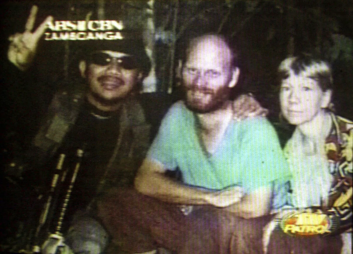 Kidnapped American missionaries Martin (C) and Gracia Burnham (R), who were kidnapped from a Philippines resort eight months ago, are seen beside their abductor Abu Sabaya, leader of the Abu Sayyaf terrorist group, in this undated photo made from video. (ABS CBN via AP)