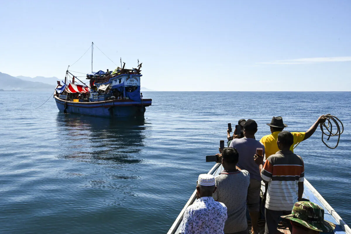 People on a relief boat approach a boat loaded with dozens of Rohingya refugees anchored off the coast of Labuhan Haji in Southern Aceh province on October 21, 2024. A boat loaded with more than 100 Rohingya refugees was spotted off Indonesia's westernmost province with at least one dead body seen on board, local officials said on October 19. (Photo by CHAIDEER MAHYUDDIN / AFP) (Photo by CHAIDEER MAHYUDDIN/AFP via Getty Images)