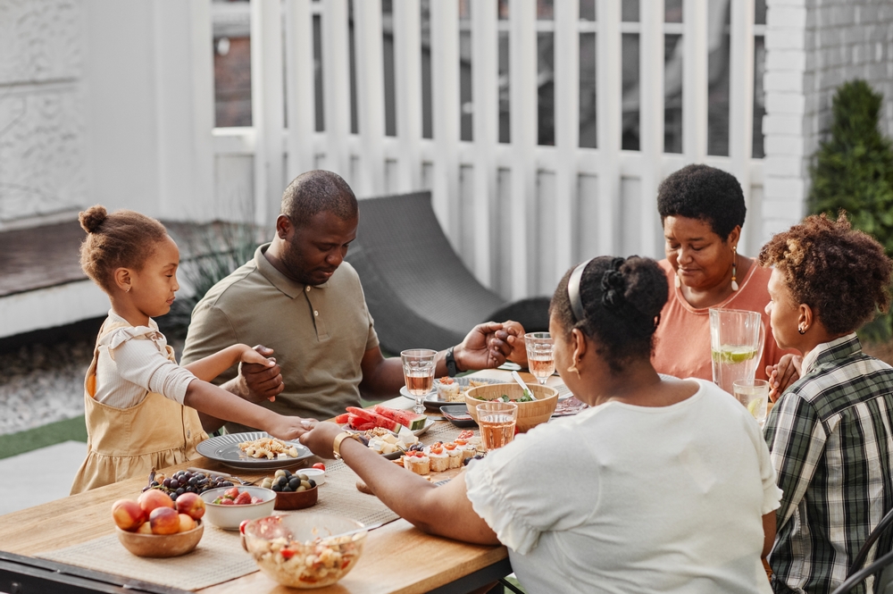 black family praying at outdoor meal