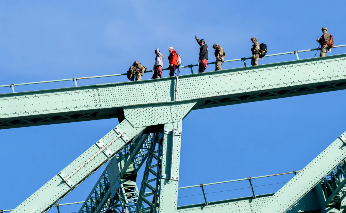 A pair of protesters are removed from the Jacques Cartier Bridge by first responders, in Montreal, on Oct. 22, 2024. (The Canadian Press/Christinne Muschi)