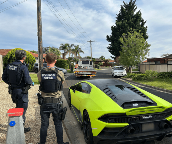 Officers from Operation Viper pictured beside one of the vehicles seized as proceeds of crime after raids on 27 properties across Victoria as part of a crackdown on a syndicate selling illegal tobacco and vapes.