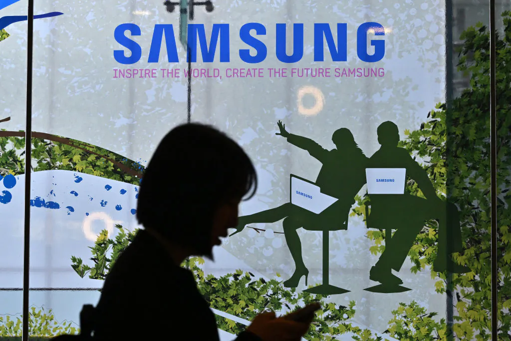 A woman walks past the Samsung logo displayed on a glass window at the company's Seocho building in Seoul on April 30, 2024. (Jung Yeon-je/AFP via Getty Images)