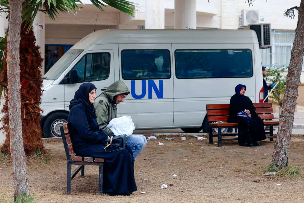 Displaced Palestinians sit on benches as they wait outside a clinic of the U.N. Relief and Works Agency for Palestine Refugees in Rafah in the southern Gaza Strip, on Jan. 28, 2024. (AFP via Getty Images)