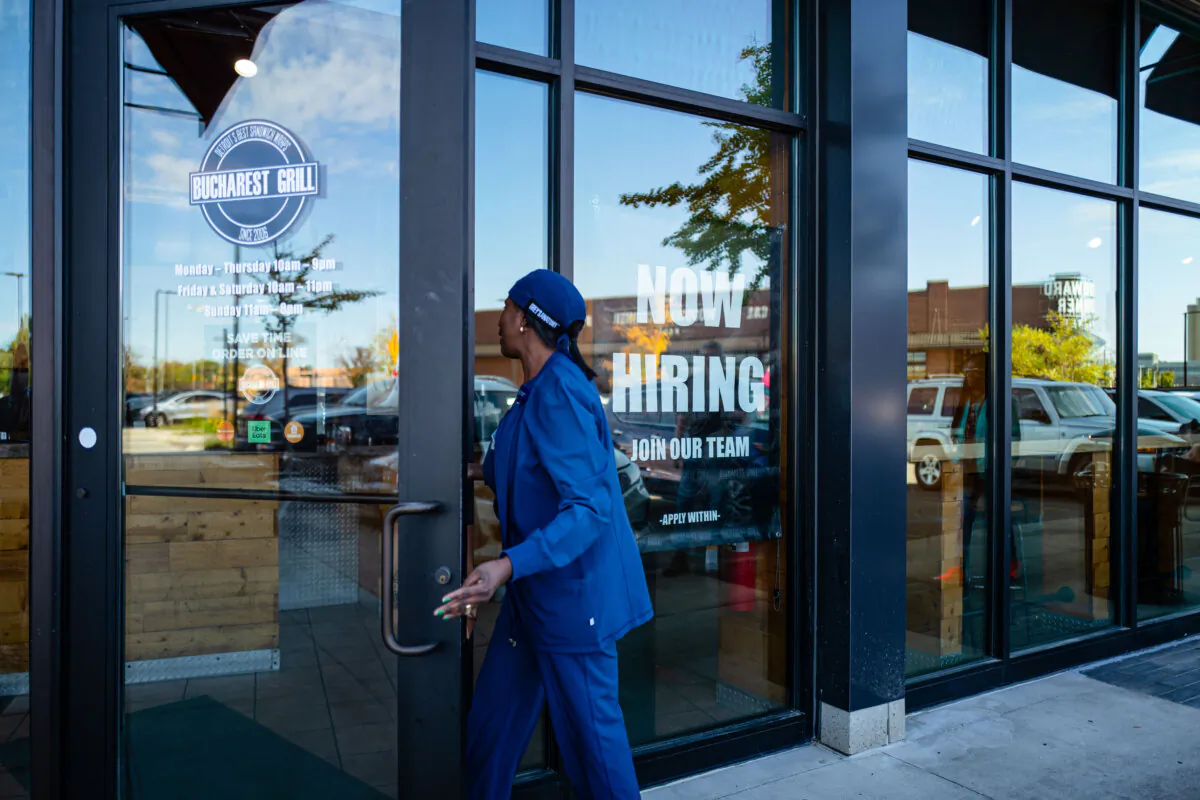 A woman walks into a restaurant displaying a hiring sign in Royal Oak, Mich., on Oct. 12, 2024. (Madalina Vasiliu/The Epoch Times)
