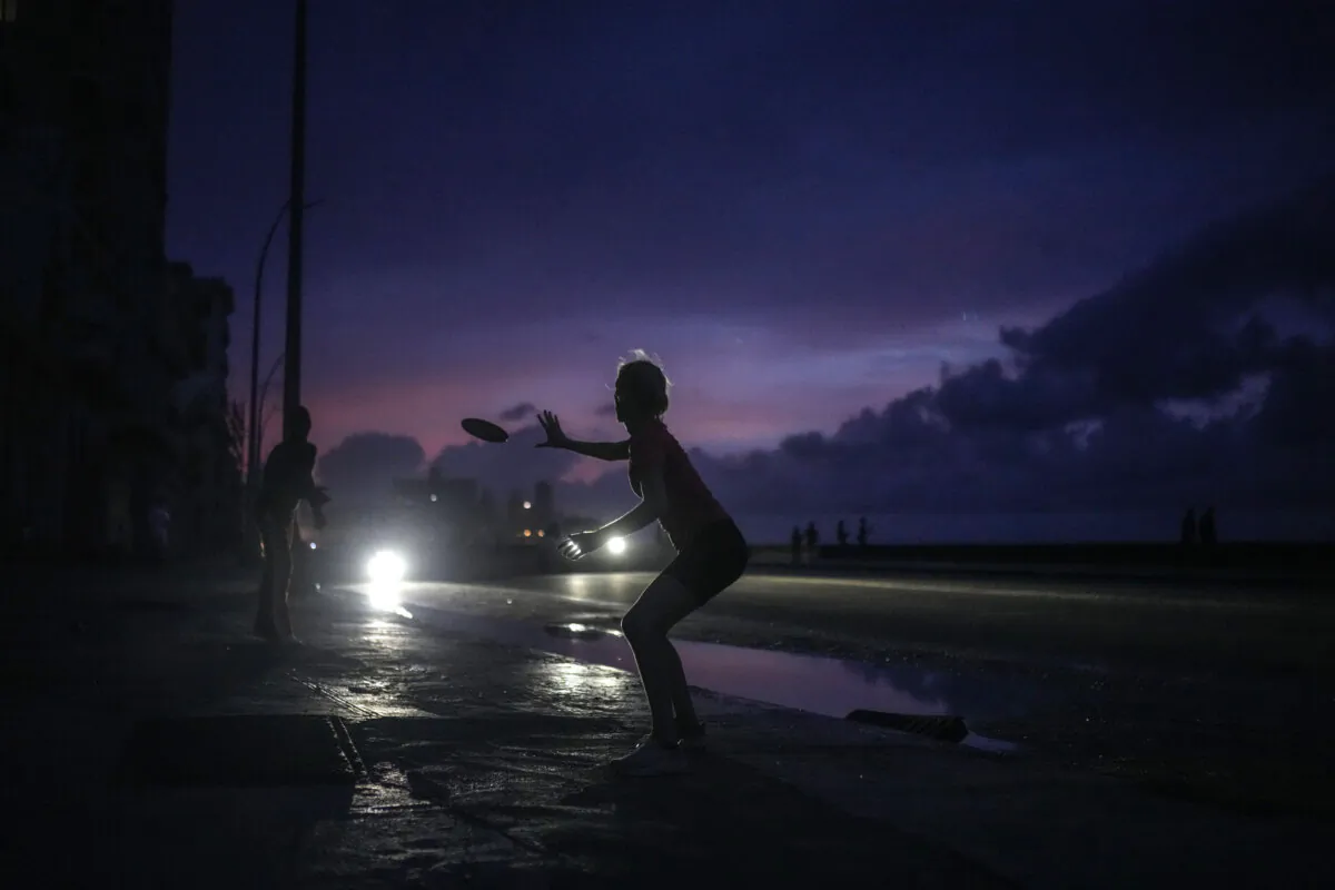 A woman prepares to catch a tossed frisbee during a massive blackout after a major power plant failed in Havana, Cuba, on Oct. 18, 2024. (Ramon Espinosa/AP Photo)
