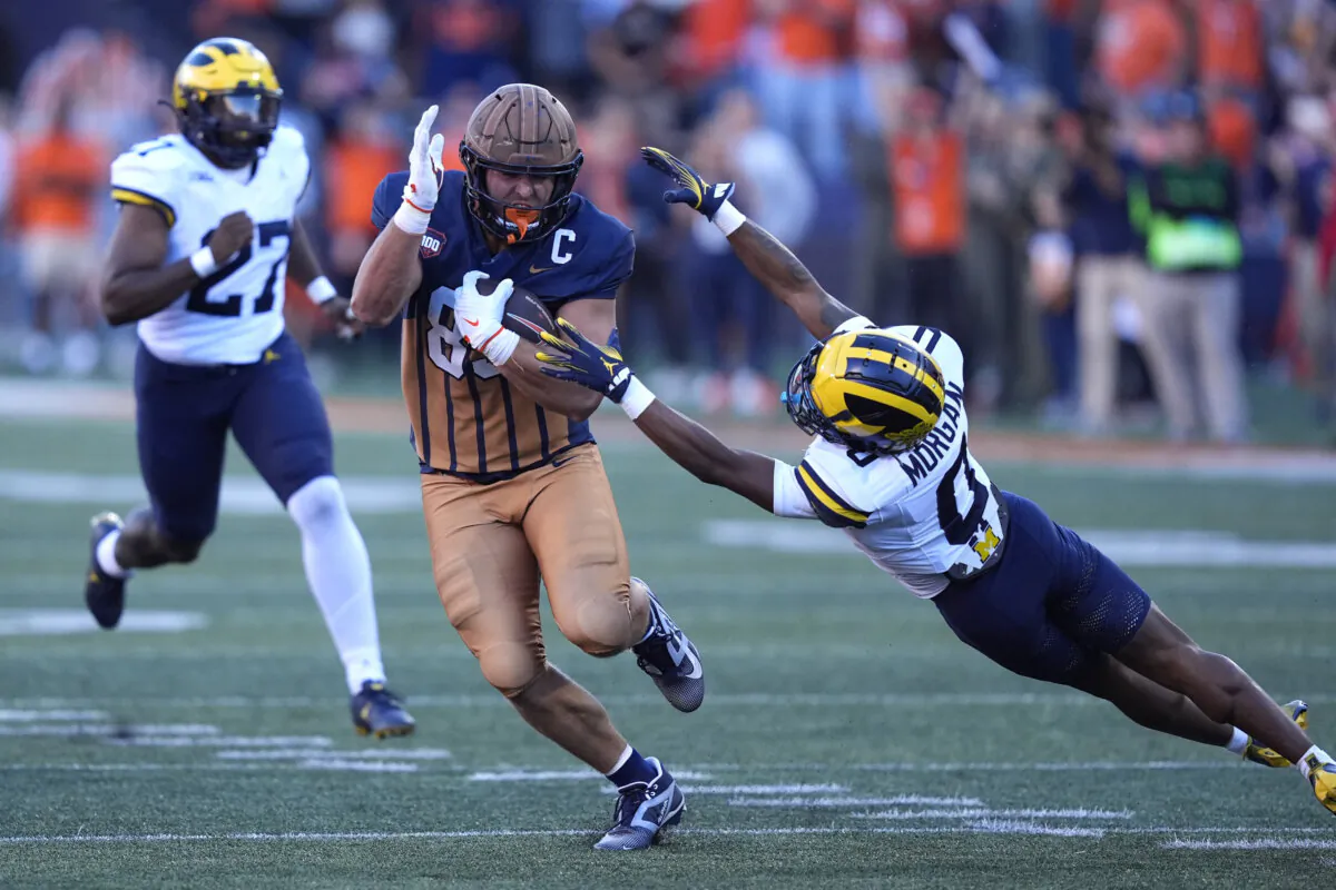 Illinois tight end Tanner Arkin sidesteps a tackle by Michigan's Semaj Morgan on a fake punt during the second half of an NCAA college football game Saturday, Oct. 19, 2024, in Champaign, Ill. (AP Photo/Charles Rex Arbogast)