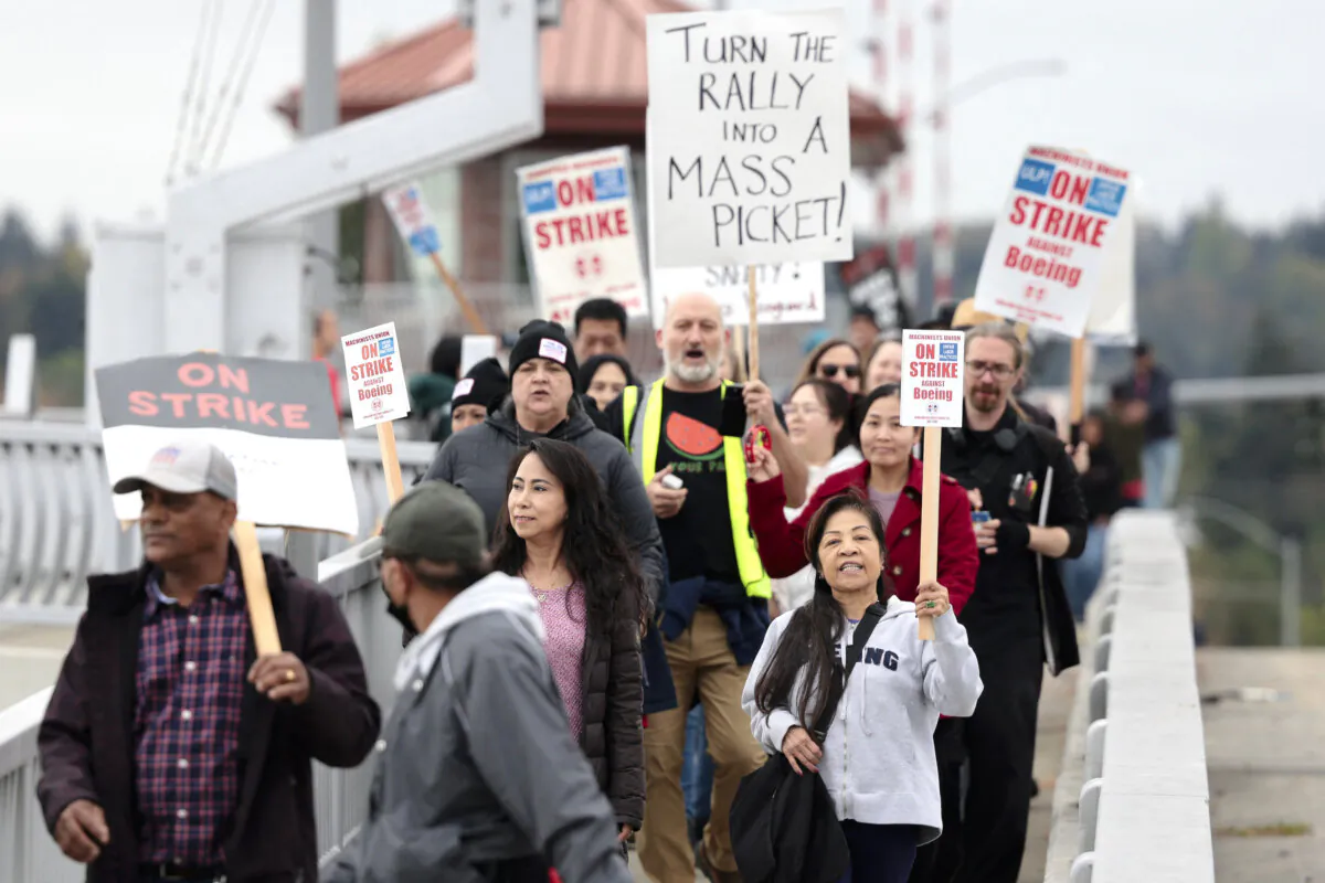 People carry signs as they march toward Boeing Field following a strike rally for the International Association of Machinists and Aerospace Workers (IAM) at the Seattle Union Hall in Seattle on Oct. 15, 2024. (Jason Redmond/AFP via Getty Images)