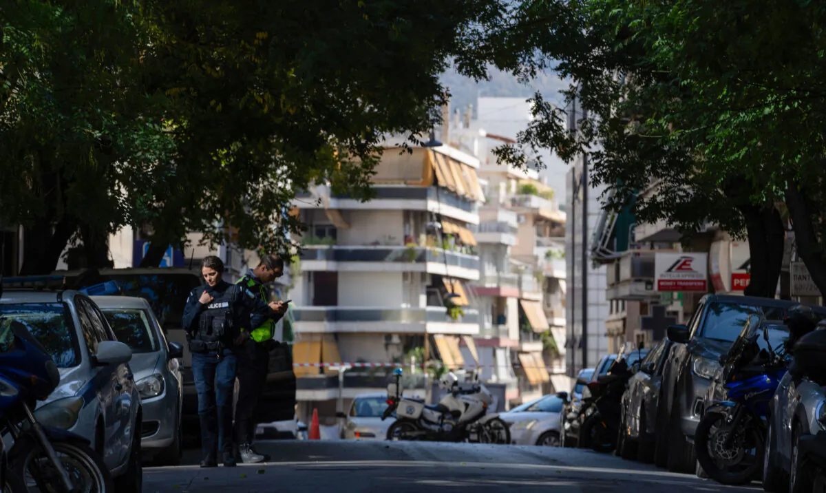 Police officers guard near the entrance of a building following an explosion, which police believe was caused by an improvised device, that killed a man and a woman was seriously wounded, in Athens, on Friday, Nov. 1, 2024 (AP Photo/Petros Giannakouris)