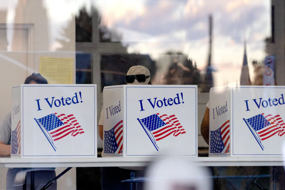 People complete their ballots as the sunset is reflected in the glass of a precinct in the Bloomfield neighborhood of Pittsburgh, Pennsylvania, on November 5, 2024. (Photo by Rebecca DROKE / AFP) (Photo by REBECCA DROKE/AFP via Getty Images)
