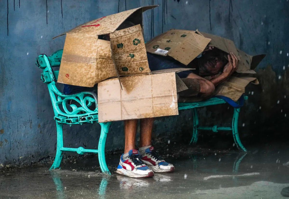 People at a bus stop shield themselves with cardboard amid wind and rain during the passage of Hurricane Rafael in Havana, Cuba, on Nov. 6, 2024. (AP Photo/Ramon Espinosa)