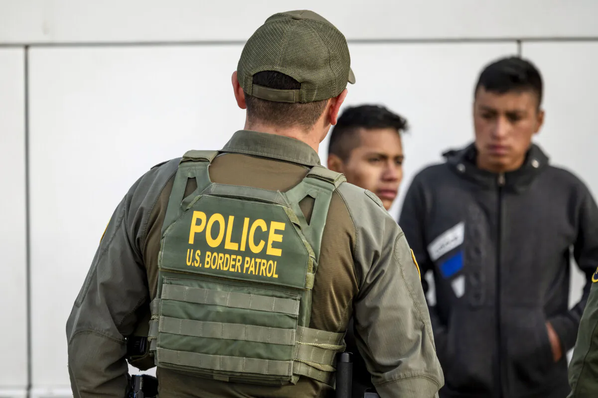 Border Patrol agent watches as immigrants prepare to board a bus after crossing the U.S.-Mexico border in Eagle Pass, Texas on Jan. 07, 2024. (John Moore/Getty Images)
