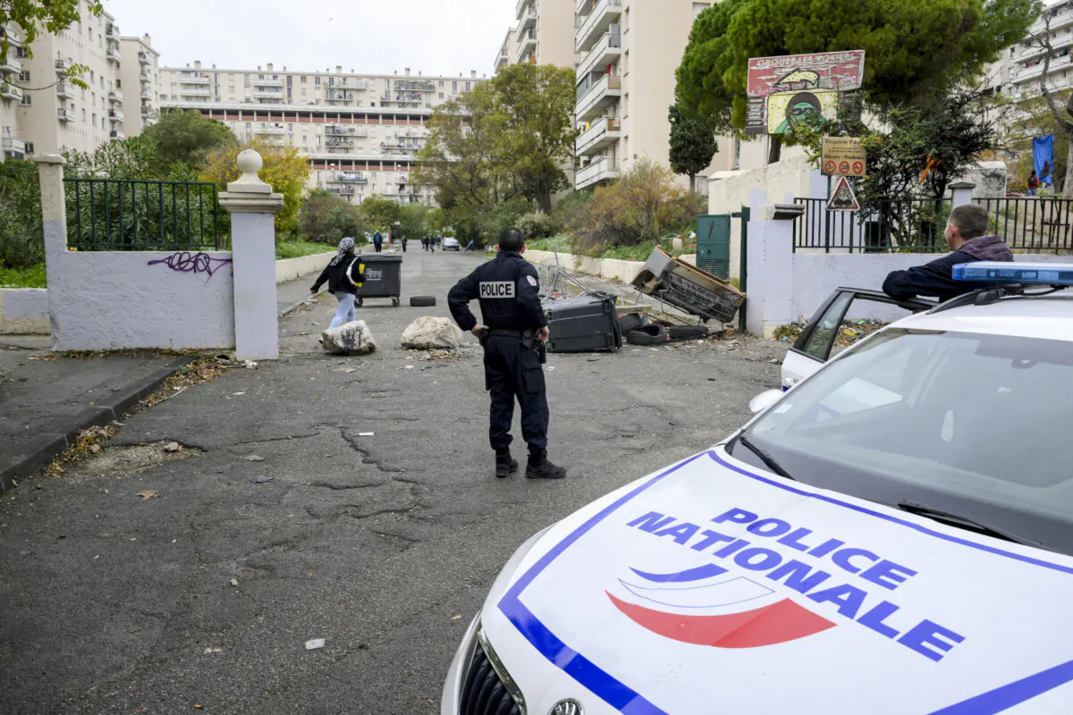 A police officer from the BST 14 Brigade, specialised in drug trafficking, stands next to a barricade at the entrance of the Les Rosiers housing project in the northern district of Marseille, southern France, on Dec. 1, 2023. (Nicolas Tucat/AFP via Getty Images)