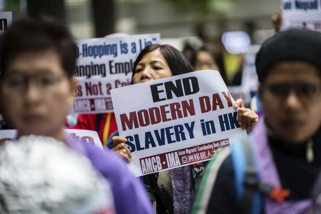 An activist from the Asian Migrants Coordinating Body holds a placard that reads "End Modern Day Slavery in HK" during a protest urging the Immigration Department to review its accommodation and visa polices for foreign domestic helpers on International Women's Day in Hong Kong on March 8, 2018. (ANTHONY WALLACE/AFP via Getty Images)