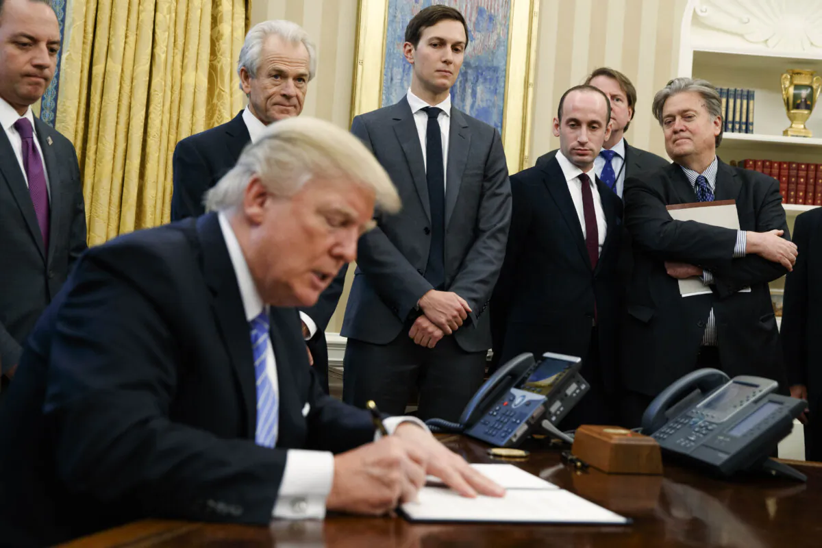 Then-White House Chief of Staff Reince Priebus, then-National Trade Council adviser Peter Navarro, then- Senior Adviser Jared Kushner, then- policy adviser Stephen Miller, and then-chief strategist Steve Bannon watch as former President Donald Trump signs an executive order in the Oval Office of the White House in Washington on Jan. 23, 2017. (AP Photo/Evan Vucci)