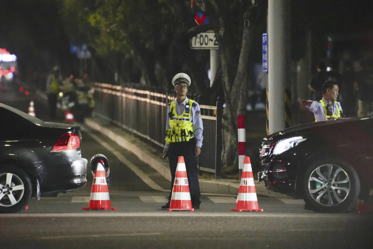A security guard stands near a sports center where a man rammed a car into people exercising, in Zhuhai, China, Nov. 11, 2024. (Kyodo News via AP)