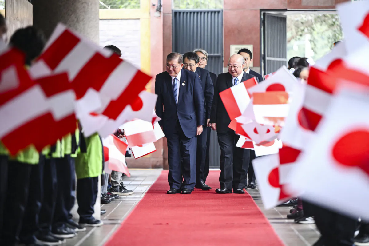 Japanese Prime Minister Shigeru Ishiba (L) bows to children waving Japanese and Peruvian national flags upon his arrival for a meeting with members of the Peruvian–Japanese community at the Peruvian Japanese Association in Lima, Peru, on Nov. 17, 2024. (Ernesto Benavides/AFP via Getty Images)