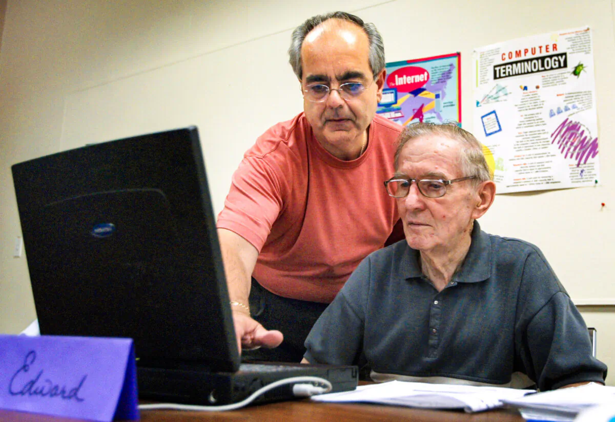 An instructor helps an 83-year-old man as he works on his laptop computer in Des Plaines, Ill., in this file photo. (Tim Boyle/Getty Images)