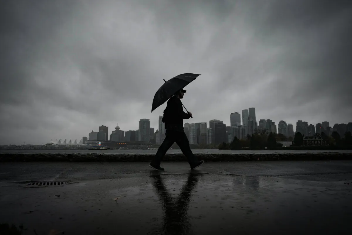 A man uses an umbrella to shield himself from the rain in Vancouver, on Oct. 19, 2024. (The Canadian Press/Darryl Dyck)
