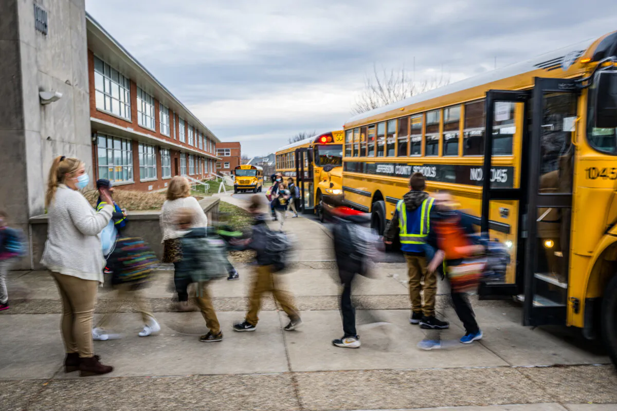 A teacher waves to her students as they get off the bus at Carter Traditional Elementary School in Louisville, Ky., on Jan. 24, 2022. (Jon Cherry/Getty Images)