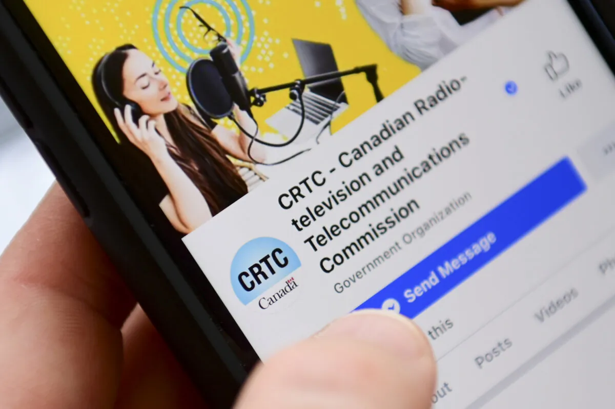 A person navigates to the online social media pages of the CRTC on a cell phone in a file photo. (The Canadian Press/Sean Kilpatrick)