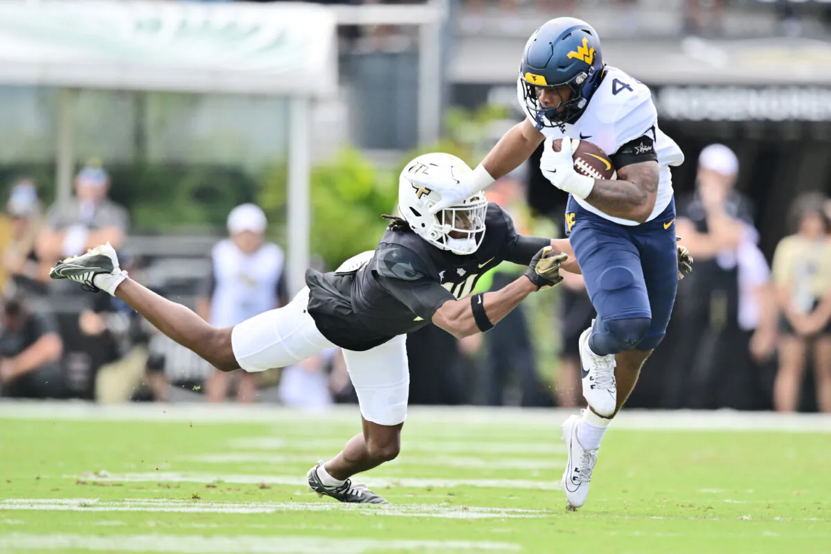 CJ Donaldson Jr. #4 of the West Virginia Mountaineers breaks a tackle from Corey Thornton #14 of the UCF Knights in the first half of a game at FBC Mortgage Stadium on October 28, 2023 in Orlando, Florida. (Julio Aguilar/Getty Images)