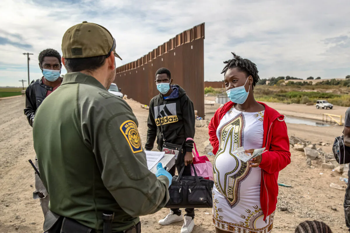 Illegal immigrants, including a pregnant Haitian woman seeking to give birth in the United States, are apprehended by a U.S. Border Patrol agent in Yuma, Ariz., on Dec. 7, 2021. (John Moore/Getty Images)