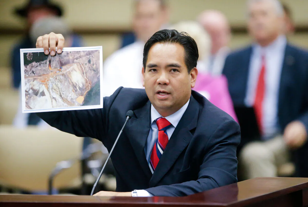 Utah Attorney General Sean Reyes holds a photograph from the spill from the Colorado gold mine during the State Water Development Commission meeting in Salt Lake City on Aug. 18, 2015. Reyes told Utah lawmakers that legal action will be on the table if EPA response to the spill falls short. (AP Photo/Rick Bowmer)
